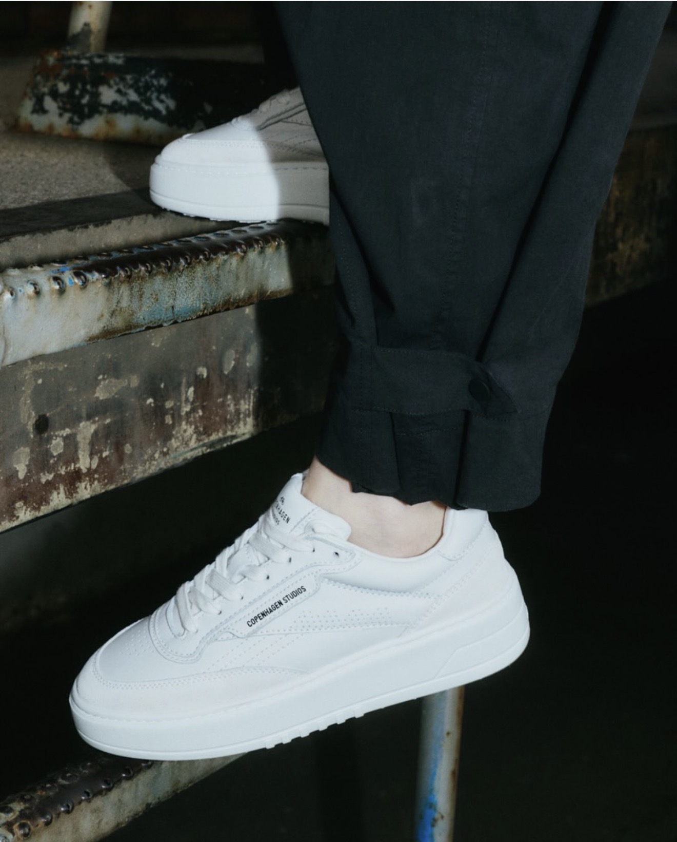 Weiße Sneaker von Copenhagen Studios auf einer Metalltreppe